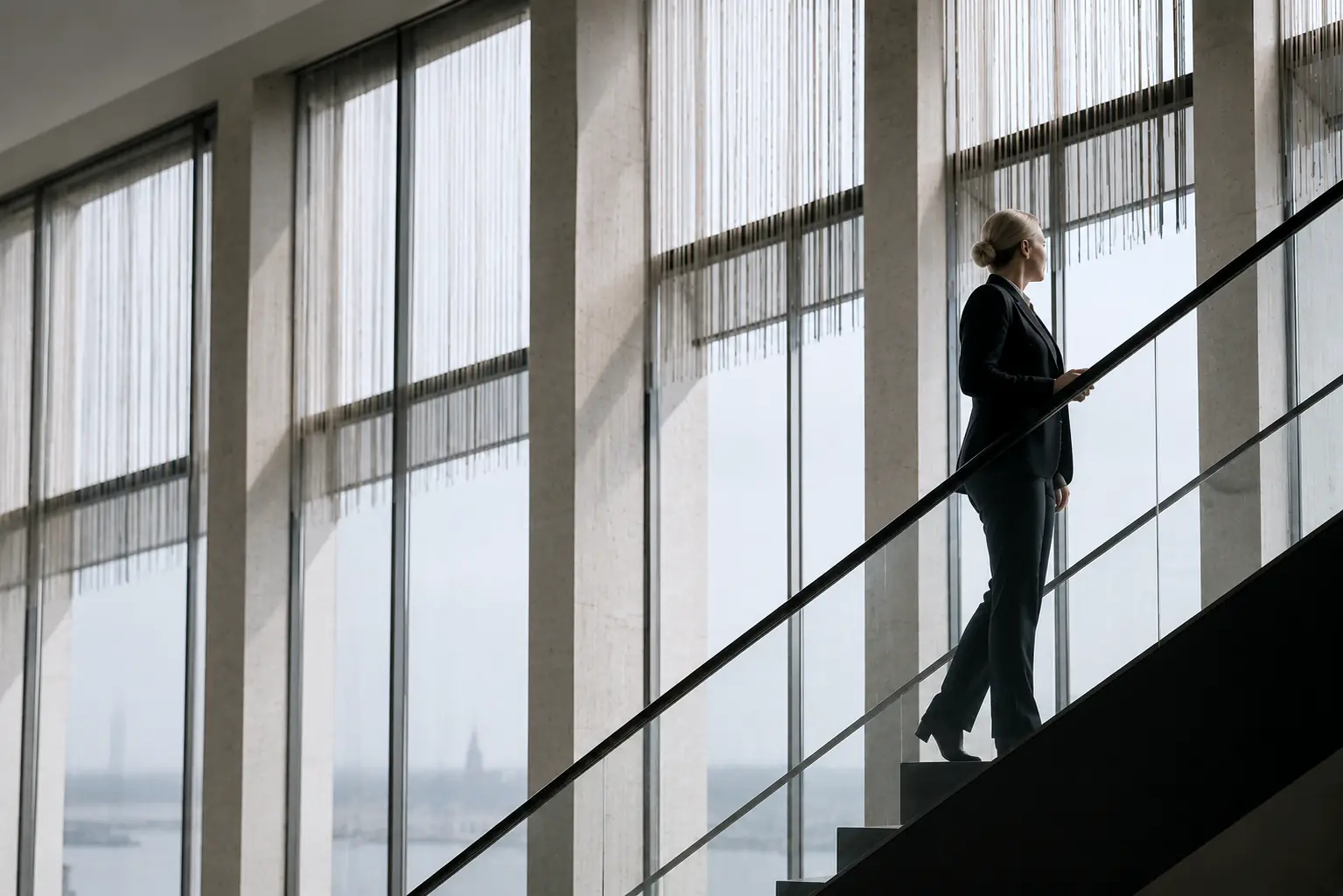 Zane Lulle-Ertmane on a staircase in a Baltic office tower, city visible beyond
